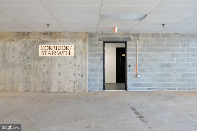 interior space with concrete block wall and a paneled ceiling