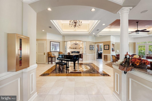 foyer with ornate columns, arched walkways, ornamental molding, a raised ceiling, and a decorative wall