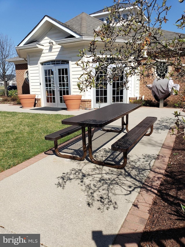 back of property with brick siding, a patio area, french doors, and a yard