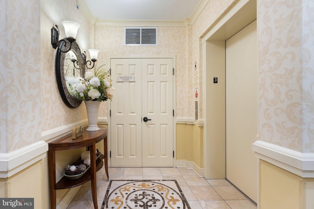 foyer entrance featuring visible vents, wallpapered walls, ornamental molding, elevator, and light tile patterned floors