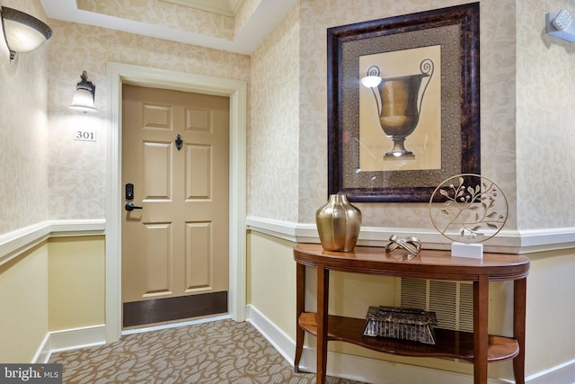 carpeted foyer entrance with wallpapered walls and baseboards