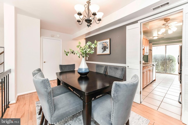 dining room with visible vents, light wood-style floors, and ceiling fan with notable chandelier