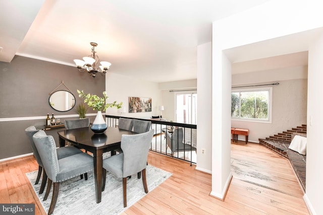 dining space with baseboards, an inviting chandelier, and hardwood / wood-style flooring