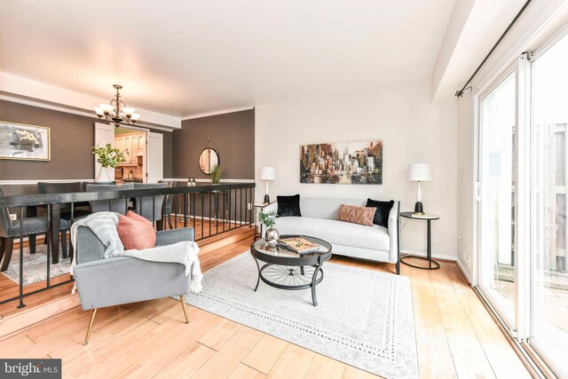 living room featuring baseboards, a notable chandelier, and hardwood / wood-style flooring