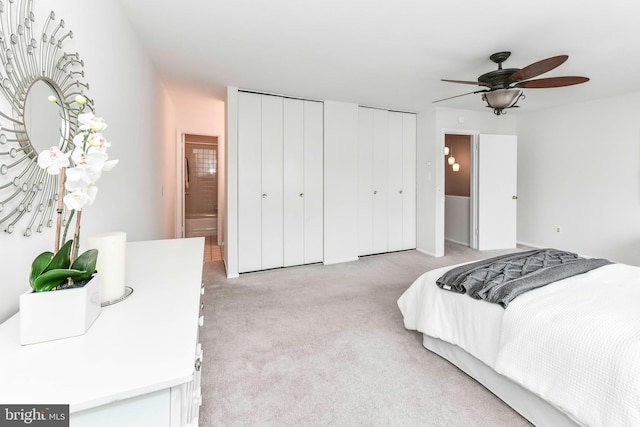 bedroom with light colored carpet and two closets