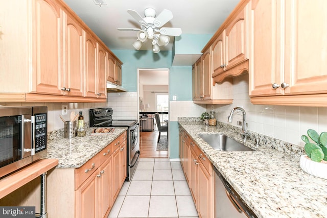 kitchen featuring a sink, light stone counters, appliances with stainless steel finishes, light tile patterned floors, and decorative backsplash