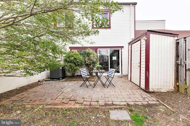 view of patio featuring an outbuilding, a shed, central AC, and fence