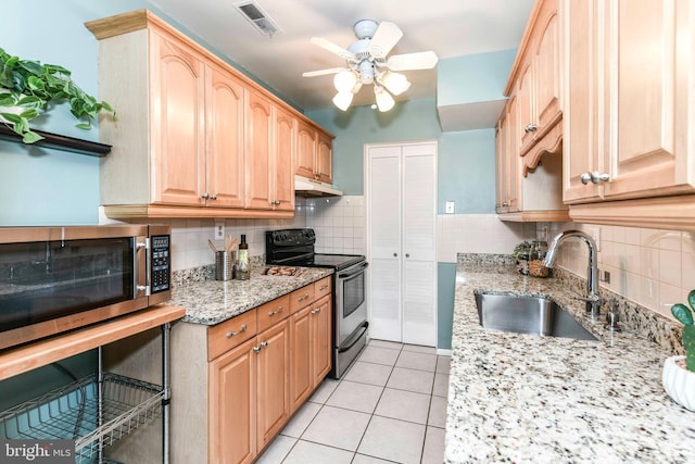 kitchen featuring visible vents, under cabinet range hood, appliances with stainless steel finishes, light tile patterned flooring, and a sink