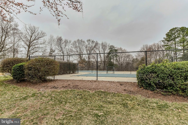 view of basketball court with a tennis court and fence