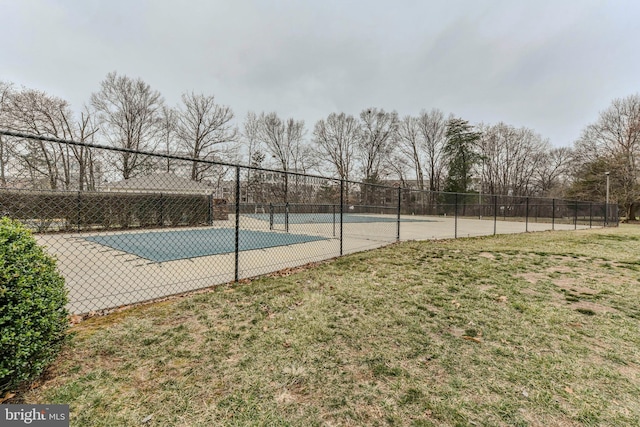 view of tennis court featuring fence and a lawn