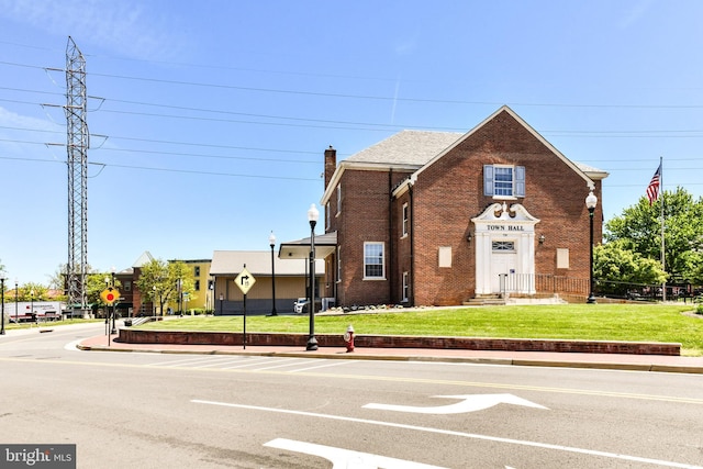 view of front of property with a front lawn, brick siding, a chimney, and fence