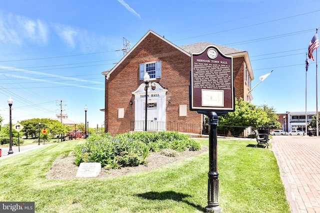 view of front of house with brick siding, a front yard, and fence