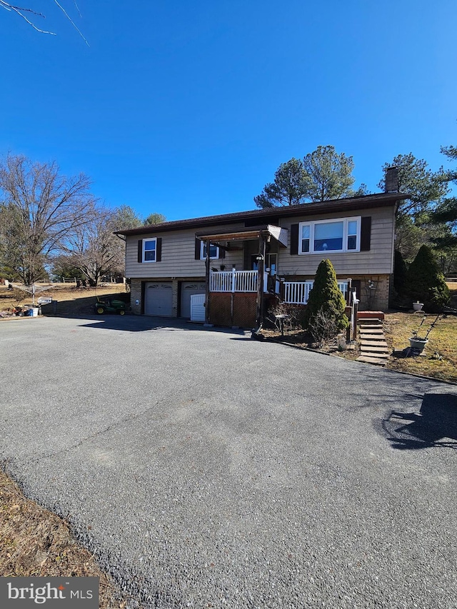 view of front of property with driveway, a chimney, and a garage