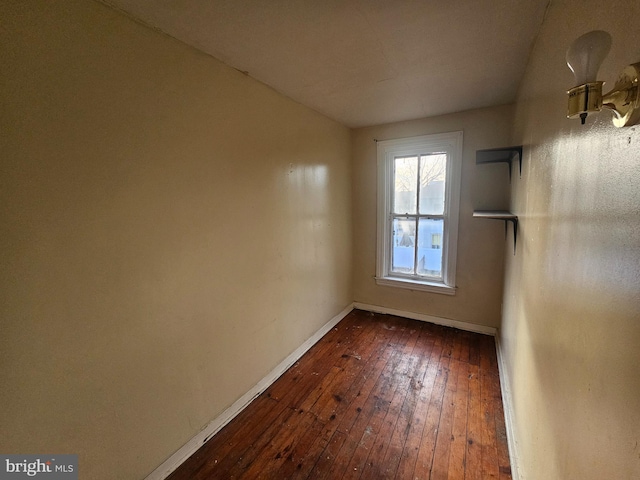 unfurnished room featuring baseboards and dark wood-style flooring