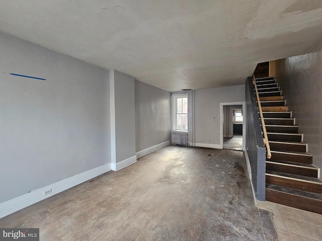 unfurnished living room featuring stairs, radiator heating unit, and baseboards