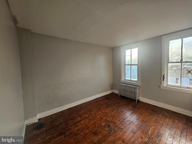 spare room featuring baseboards, radiator, and dark wood-style floors