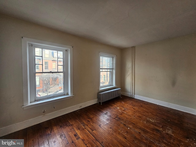 spare room with radiator, baseboards, and wood-type flooring