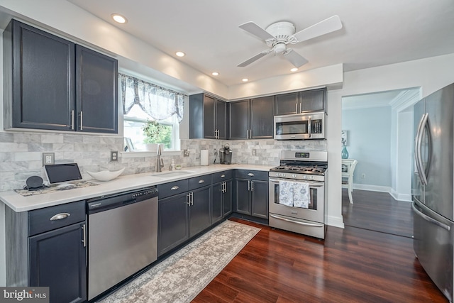 kitchen featuring dark wood-style flooring, a sink, light countertops, appliances with stainless steel finishes, and backsplash