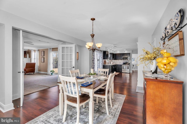 dining area featuring ceiling fan with notable chandelier, baseboards, and dark wood-style flooring