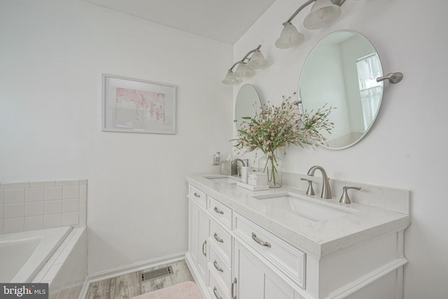 bathroom with double vanity, wood finished floors, visible vents, and a sink