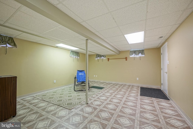 finished basement with tile patterned floors, a paneled ceiling, and baseboards