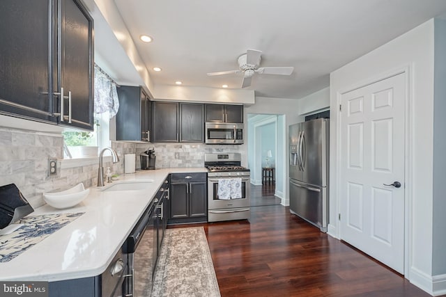 kitchen featuring dark wood-style flooring, a sink, decorative backsplash, light countertops, and stainless steel appliances