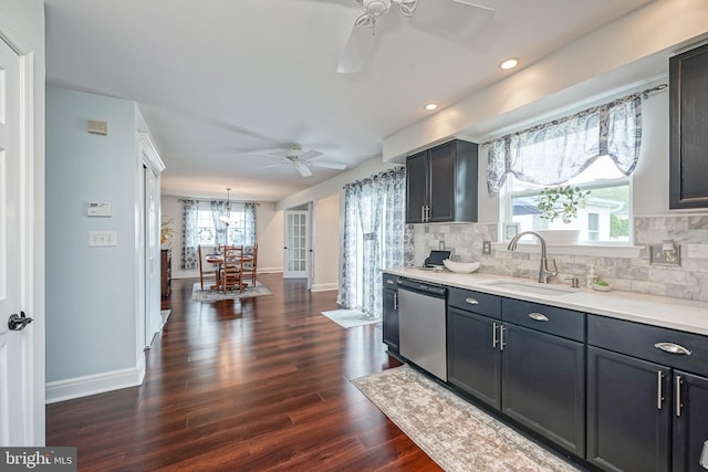 kitchen featuring light countertops, decorative backsplash, stainless steel dishwasher, dark wood-style floors, and a sink