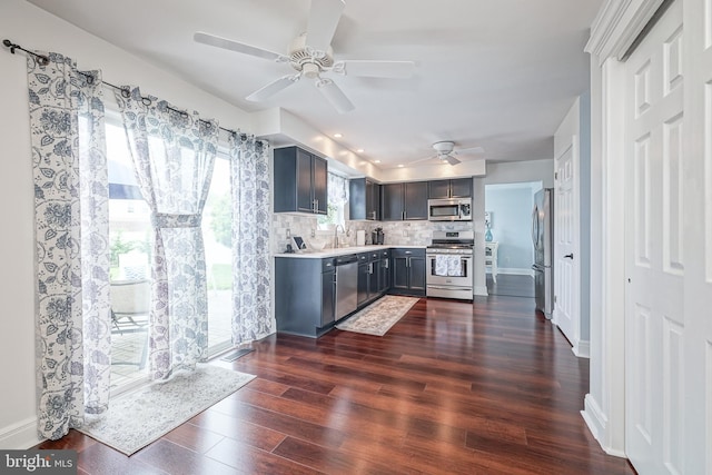 kitchen with backsplash, light countertops, appliances with stainless steel finishes, dark wood-style floors, and a sink