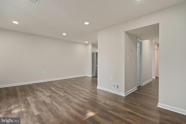 spare room featuring dark wood-style floors, visible vents, recessed lighting, and baseboards