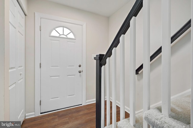 foyer entrance with dark wood finished floors, stairs, and baseboards