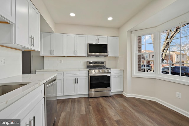 kitchen with tasteful backsplash, baseboards, dark wood finished floors, light stone counters, and stainless steel appliances