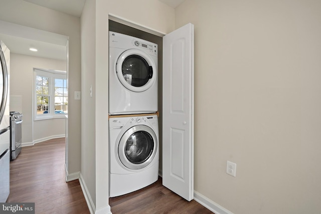 laundry area with baseboards, dark wood-style flooring, laundry area, and stacked washing maching and dryer