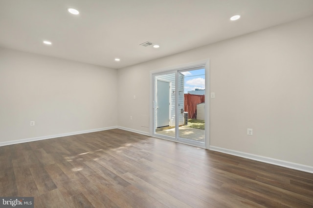 spare room featuring recessed lighting, dark wood-type flooring, and baseboards