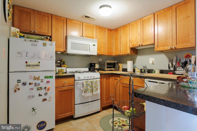 kitchen featuring white appliances, visible vents, a toaster, a sink, and dark countertops