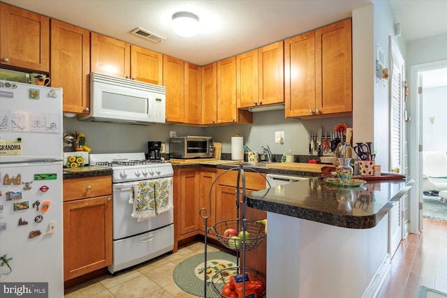 kitchen featuring visible vents, dark countertops, white appliances, a peninsula, and a toaster