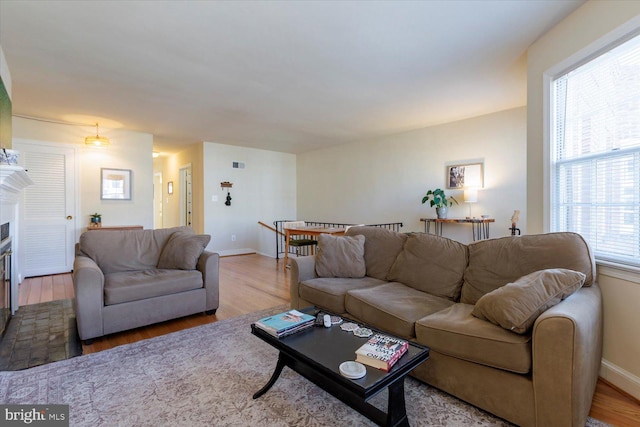 living area featuring a glass covered fireplace, baseboards, and wood finished floors