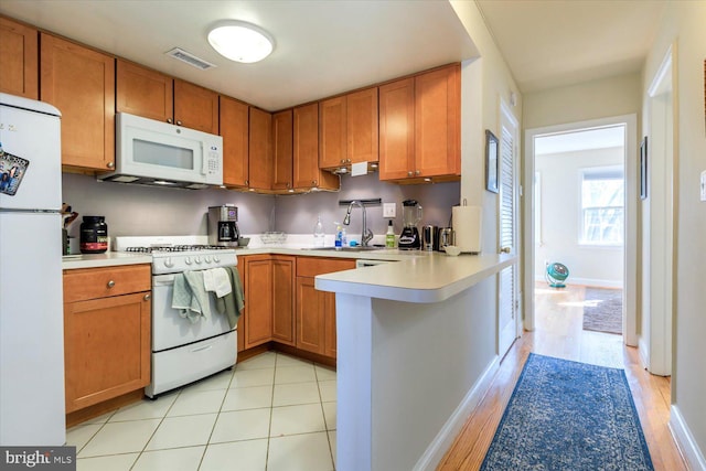 kitchen with visible vents, light countertops, brown cabinets, white appliances, and a sink