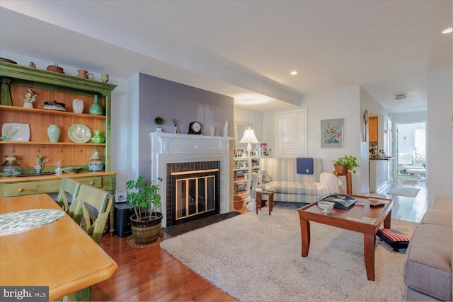 living area featuring recessed lighting, a fireplace with flush hearth, and wood finished floors