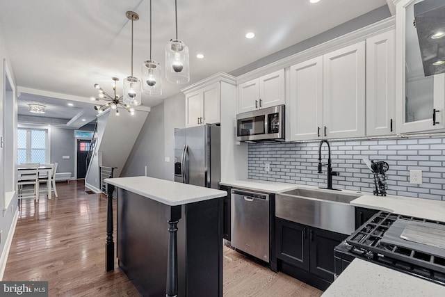 kitchen featuring a sink, a kitchen island, white cabinetry, stainless steel appliances, and light wood-style floors