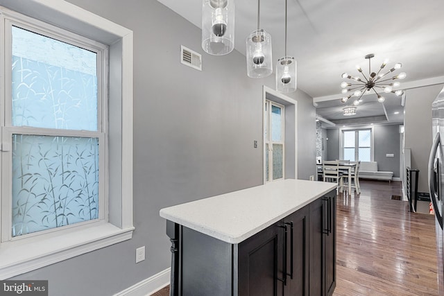 kitchen featuring visible vents, a center island, baseboards, pendant lighting, and wood finished floors