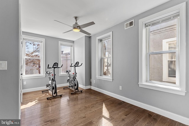 exercise room with ceiling fan, wood finished floors, visible vents, and baseboards