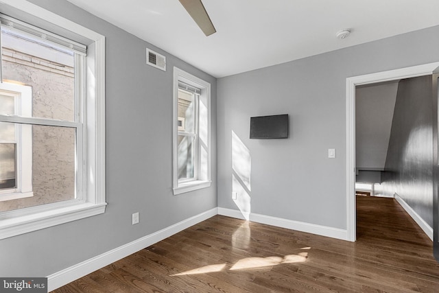 interior space featuring ceiling fan, visible vents, baseboards, and dark wood finished floors