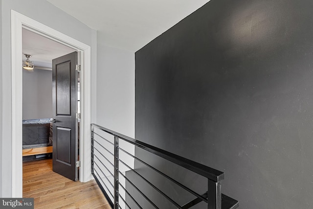 corridor featuring an upstairs landing and light wood-style flooring