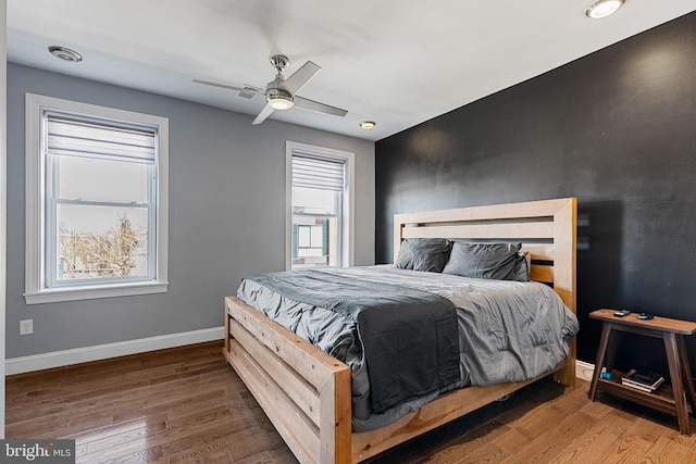 bedroom with visible vents, multiple windows, wood finished floors, and baseboards