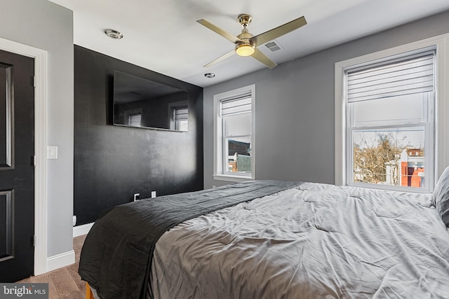 bedroom featuring wood finished floors, visible vents, baseboards, and ceiling fan