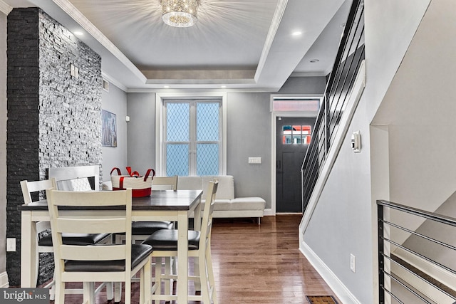 dining room featuring wood finished floors, baseboards, ornamental molding, stairs, and a raised ceiling