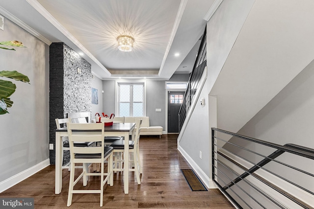 dining space with a raised ceiling, wood finished floors, and ornamental molding