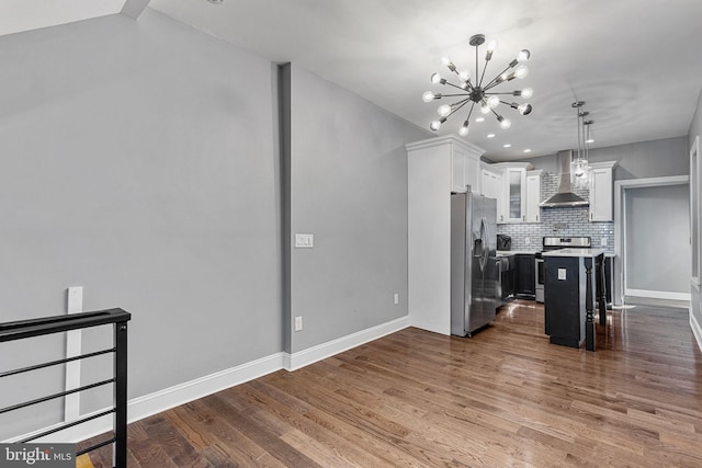 kitchen with backsplash, wall chimney range hood, appliances with stainless steel finishes, dark wood-style floors, and white cabinets