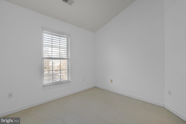 empty room with vaulted ceiling, carpet flooring, baseboards, and visible vents