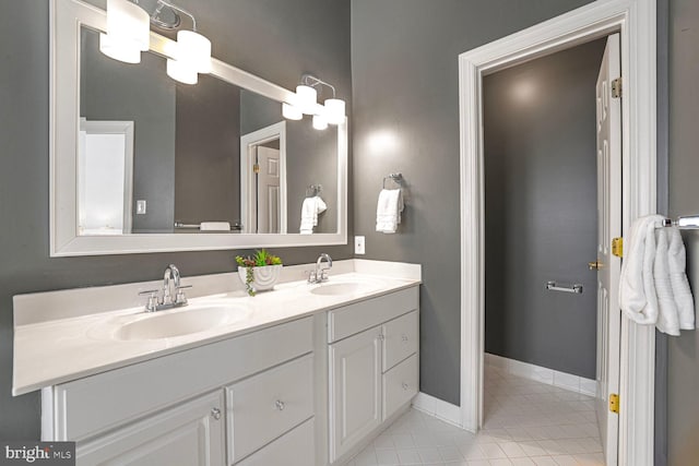 bathroom featuring a sink, baseboards, double vanity, and tile patterned floors